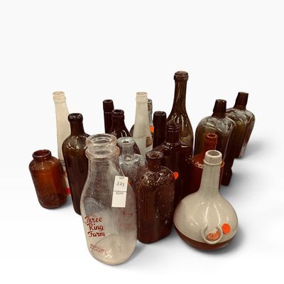 Collection of vintage glass bottles and stoneware, featuring a Three Ring Farm milk bottle and various amber and clear glass...
