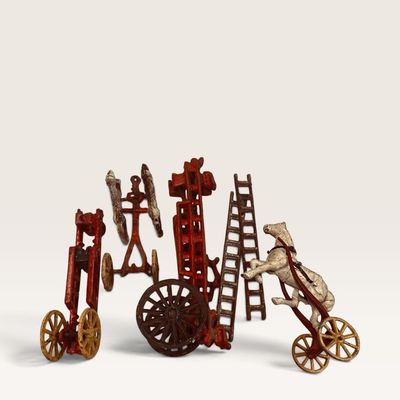 Vintage painted cast iron fire wagon toy components, including ladders, spoked wheels, and a horse team frame.
