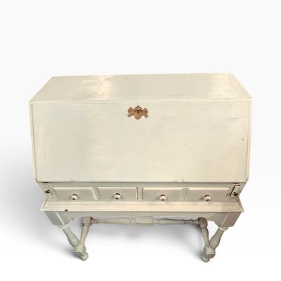 Vintage white painted slant-front secretary desk featuring turned legs, stretcher base, and four small lower drawers.