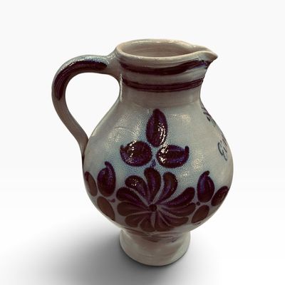 Sale Photo Thumbnail #31: Handcrafted German salt-glazed stoneware pottery pitcher featuring deep cobalt blue floral motifs on a light grey background.