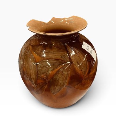 Glazed brown pottery vase featuring embossed leaf details, showing significant damage and chipping along the flared rim.