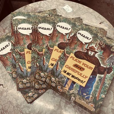 Stack of vintage 1978 Smokey Bear and Bic lighter promotional posters on a round table top.