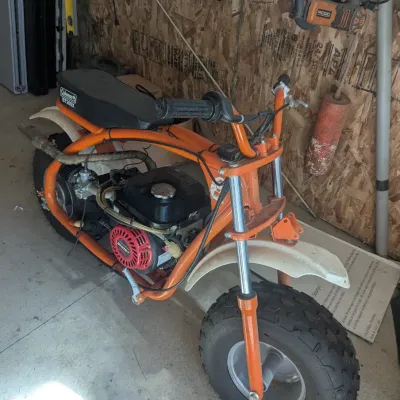 Sale Photo Thumbnail #14: Coleman BT200X mini bike with an orange tubular frame, black padded seat, and an upgraded Predator Ghost engine.