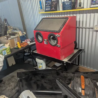 Sale Photo Thumbnail #8: Red Central Pneumatic benchtop abrasive blast cabinet mounted on a metal utility cart, shown alongside workshop tools and equipment.