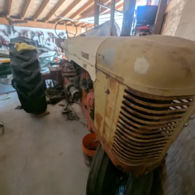 Sale Photo Thumbnail #12: Vintage Case narrow-front farm tractor with cream and orange paint, stored inside a workshop.