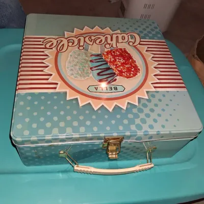 Sale Photo Thumbnail #680: BELLA CAKESICLE MAKER IN ORIGINAL TIN LUNCHBOX STYLE STORAGE BOX. INCLUDES MAKER, INSTRUCTION MANUAL, DECORATING SYRINGE TOOL, STICKS AND MORE. APPEARS LIGHTLY USED OR UNUSED IN ORIGINAL PACKAGING.