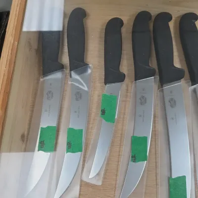 Sale Photo Thumbnail #77: Collection of Victorinox professional kitchen knives with black Fibrox handles, presented inside a glass display case.