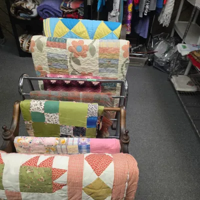 Sale Photo Thumbnail #34: Collection of handmade vintage quilts, woven blankets, and textiles displayed on wooden quilt racks.