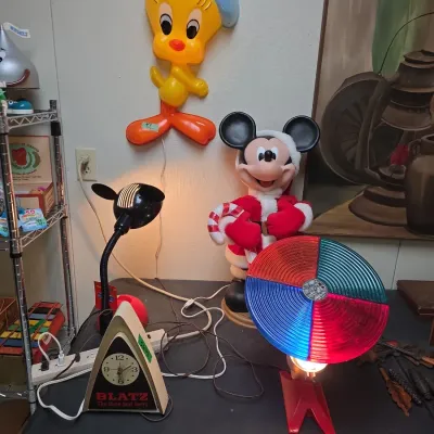 Sale Photo Thumbnail #46: Collection of vintage novelty lighting and decor, including a wall-mounted Tweety Bird light, a Santa Mickey Mouse figure, a Blatz beer clock, and a rotating color wheel lamp.