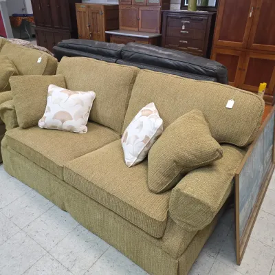 Sale Photo Thumbnail #10: Contemporary olive green textured fabric sofa with matching side pillows and leaf-patterned accent pillows, surrounded by wooden cabinets.