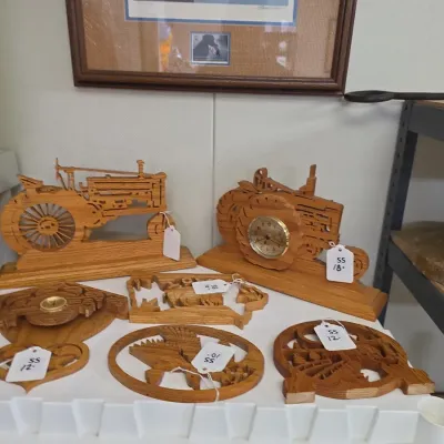 Sale Photo Thumbnail #59: Collection of scroll-saw oak woodwork pieces, featuring tractor-themed desk clocks and wildlife wall plaques.