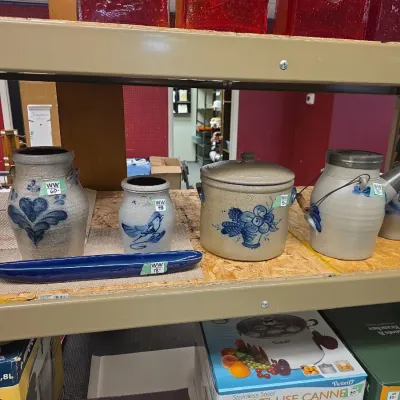 Sale Photo Thumbnail #40: Collection of blue-and-white cobalt decorated stoneware crocks and pottery pieces displayed on a shelf alongside boxed kitchenware.