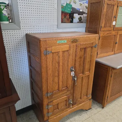 Sale Photo Thumbnail #18: Vintage Herrick oak icebox cabinet featuring ornate metal hardware and paneled wooden doors.