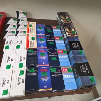 Sale Photo Thumbnail #87: Large assortment of reloading primers from brands like CCI, Winchester, and Federal, displayed on a wooden surface.