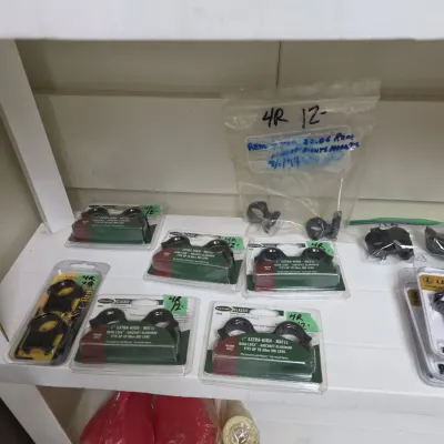 Sale Photo Thumbnail #73: Assortment of packaged Weaver Classic 1-inch extra-high matte Quad-Lock scope rings alongside additional loose hardware on a shelf.