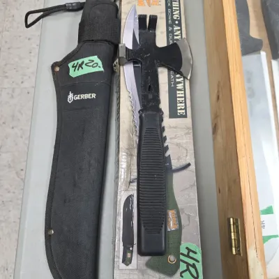 Sale Photo Thumbnail #78: Gerber machete with black nylon sheath alongside a multi-tool hatchet and boxed United Cutlery Marine Force Recon knife.