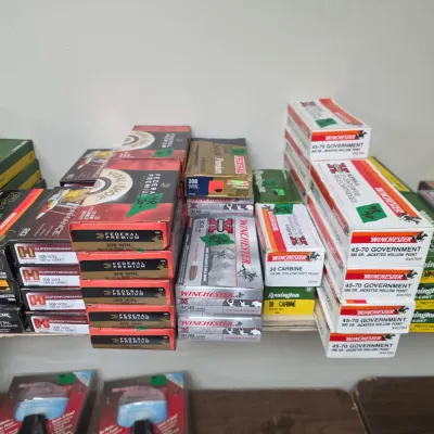 Sale Photo Thumbnail #91: Assortment of boxed rifle ammunition, including Winchester 45-70 Government, .308 Win, and .30 Carbine, alongside packaged firearm accessories.