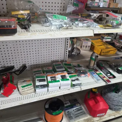Sale Photo Thumbnail #107: Assorted workshop tools and hardware displayed on pegboard retail shelving, including packaged Stihl chainsaw chains, spools of wire and line, hand tools, and a small red gas can.