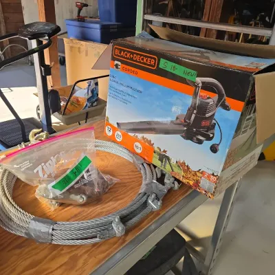 Sale Photo Thumbnail #129: Black & Decker corded 3-in-1 electric leaf blower/vacuum/mulcher in its original box, displayed alongside a coil of heavy-duty steel wire cable and hardware.