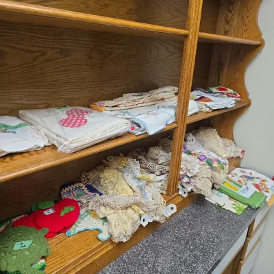 Sale Photo Thumbnail #33: Wooden hutch top shelves displaying a large collection of vintage embroidered linens, crocheted doilies, and handmade pot holders.