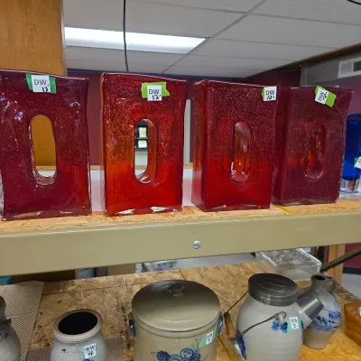 Sale Photo Thumbnail #41: Set of four red textured glass block vases displayed above various blue and gray salt-glazed stoneware crocks.