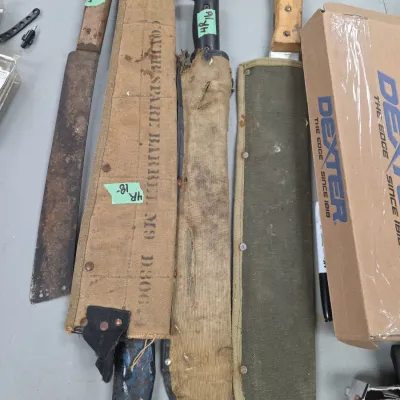Sale Photo Thumbnail #80: Collection of vintage military and utility machetes with canvas scabbards, showing age-appropriate wear and patina.