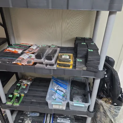 Sale Photo Thumbnail #82: Plastic shelving unit filled with firearm accessories, including gun magazines, small parts in clear storage bins, and packaged accessories.