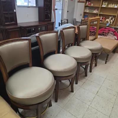 Sale Photo Thumbnail #12: Set of contemporary swivel counter barstools with dark wood frames, curved backs, and beige faux-leather upholstery.