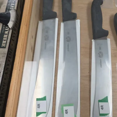 Sale Photo Thumbnail #76: Trio of Victorinox Forschner commercial butchering knives with textured black Fibrox handles, displayed inside a wooden case.