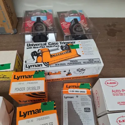Sale Photo Thumbnail #93: Collection of reloading equipment including Lyman Universal Case Trimmer, Powder Dribblers, E-Zee Case Gauge, and Lee Auto-Prime tools in original packaging.