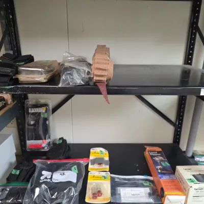 Sale Photo Thumbnail #84: Selection of tactical gear, holsters, reloading accessories, and gun maintenance items displayed on black metal shelving.