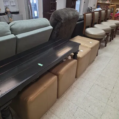 Sale Photo Thumbnail #9: Black wooden console table positioned over tan vinyl storage ottomans, alongside swivel barstools and upholstered seating.
