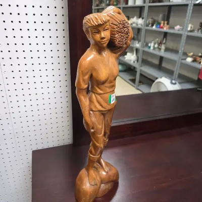 Sale Photo Thumbnail #31: Hand-carved wooden figurine depicting a person carrying a heavy burden on their shoulder, standing on an integral base.