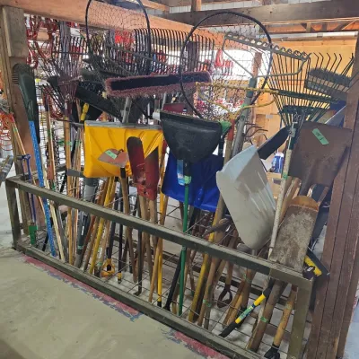 Sale Photo Thumbnail #104: Large metal rack filled with assortment of garden and yard tools, including shovels, rakes, brooms, and fishing nets.