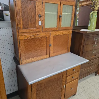 Sale Photo Thumbnail #19: Antique Hoosier oak cabinet featuring textured glass doors, an enamel work surface, and lower storage drawers.