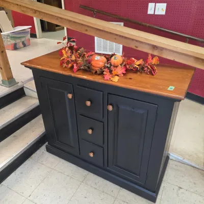 Sale Photo Thumbnail #15: Two-tone wooden cabinet featuring a black-painted base with three center drawers flanked by two side cabinets, topped with a natural stained wood surface and decorative autumn garland.