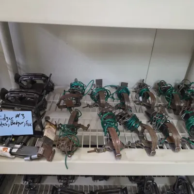 Sale Photo Thumbnail #54: Collection of vintage Bridger #3 foothold animal traps for coyotes, badgers, and foxes, displayed on wire shelving.