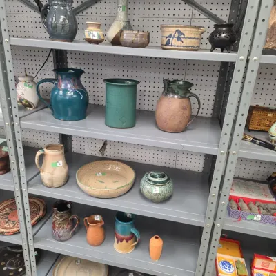 Sale Photo Thumbnail #26: Collection of studio pottery including pitchers, vases, bowls, and crocks arranged on industrial metal shelving.