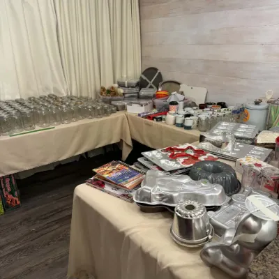 Sale Photo Thumbnail #19: Tables loaded with vintage kitchenware, including a large collection of glass canning jars, novelty aluminum cake pans, cookbooks, and glassware.