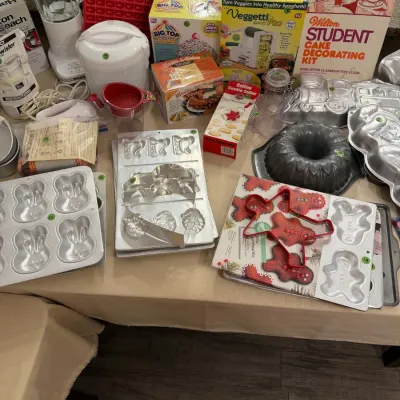 Sale Photo Thumbnail #21: Large assortment of kitchen appliances and baking supplies, including novelty cake pans, a Veggetti Pro spiralizer, a Wilton cake decorating kit, and a blender.
