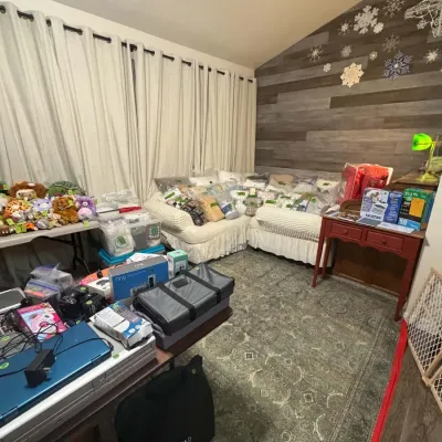 Sale Photo Thumbnail #18: Living room filled with items for sale, including plush toys, packaged bedding, and electronics.