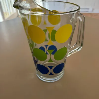 Sale Photo Thumbnail #46: Vintage mid-century modern glass pitcher featuring a bold geometric polka dot motif in yellow, green, and blue.