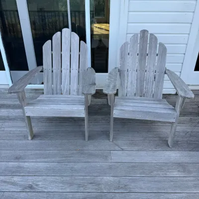 Sale Photo Thumbnail #5: Pair of weathered wooden Adirondack chairs with arched slat backs, positioned on a matching wooden deck.