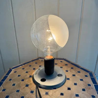 Sale Photo Thumbnail #31: Minimalist modern accent table lamp featuring an exposed clear bulb with a half-frosted white shade design on a round metal base.