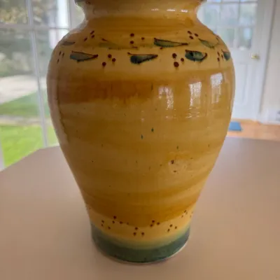 Sale Photo Thumbnail #39: Hand-thrown pottery vase featuring a mustard yellow glaze with hand-painted leaf and berry accents around the shoulder and base.