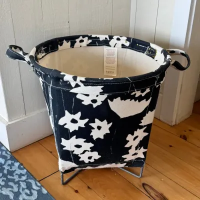 Sale Photo Thumbnail #59: Hable Construction canvas laundry hamper in a black and white floral print, set on a metal wire base with integrated fabric handles.