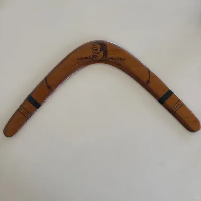 Sale Photo Thumbnail #58: Handcrafted wooden boomerang featuring pyrography artwork depicting an Aboriginal figure and landscape, finished with dark painted accent bands.