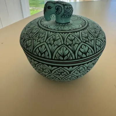Sale Photo Thumbnail #33: Hand-painted turquoise ceramic covered jar featuring a detailed floral pattern and an elephant-shaped lid finial.