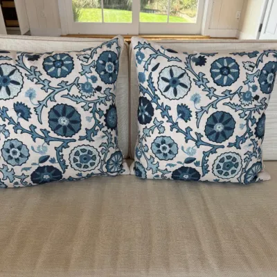 Sale Photo Thumbnail #21: Pair of square throw pillows featuring a suzani-style floral and botanical embroidery pattern in shades of blue on a cream background.