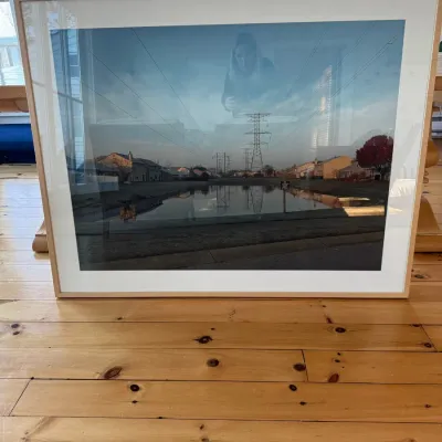 Sale Photo Thumbnail #55: Large framed photographic print depicting a suburban landscape with power lines and a reflection pond, mounted in a light wood frame with glass.